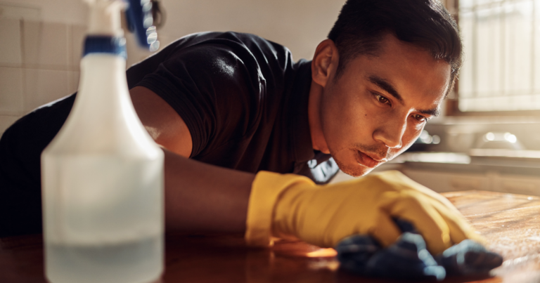 A man cleaning countertops with some all-purpose cleaner and a rag