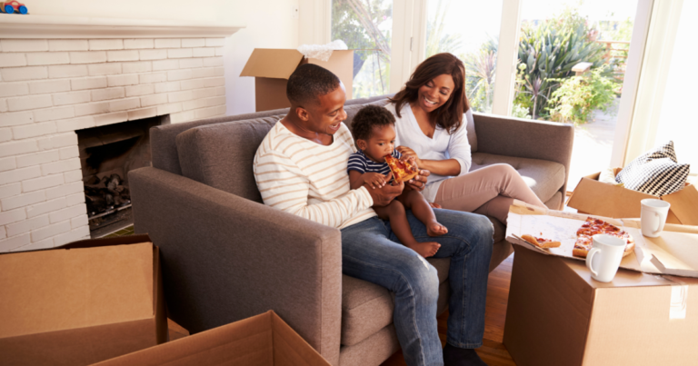 A family sits on their couch eating pizza